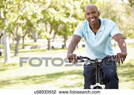 Stock Image - Young man cycling in park. Fotosearch
