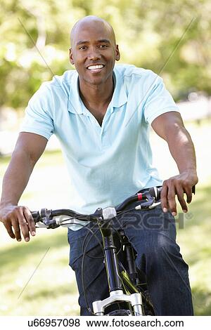 Stock Photo - Young man cycling in park. Fotosearch