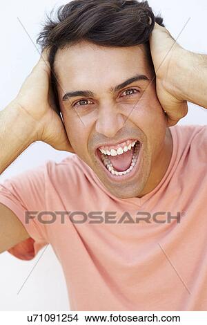 Picture - Young Man Standing By Wall With Frustrated Expression. Fotosearch