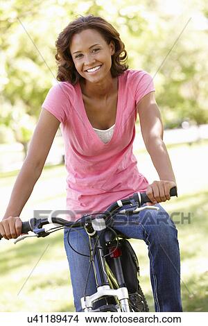 Picture - Young woman cycling in park. Fotosearch