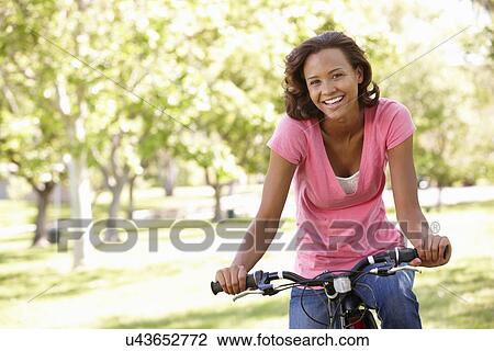 Young woman cycling in park View Large Photo Image Stock Image - Young woman cycling in park. Fotosearch