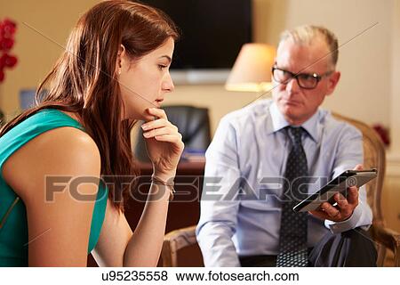 Stock Photo - Young Woman Talking To Male Counsellor Using Digital Tablet. Fotosearch