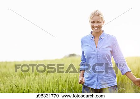 Stock Image - Young Woman Walking Through Field. Fotosearch