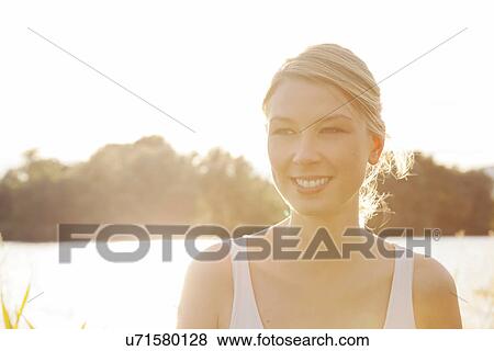 Stock Photo - Backlit portrait of young woman on riverside, Danube Island, Vienna, Austria. Fotosearch
