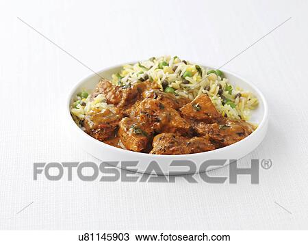 Stock Image - Bowl of chicken tikka masala and peas with steamed rice. Fotosearch