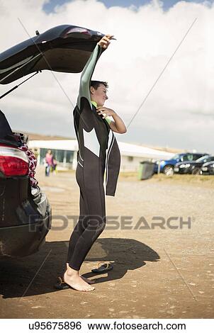 Stock Photograph - Boy putting on wetsuit by car. Fotosearch