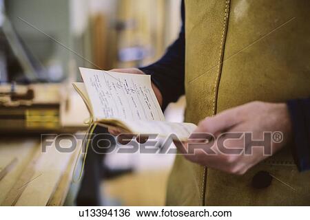 Close up of mid adult craftsman holding notebook in organ workshop View Large Photo Image Stock Photograph - Close up of mid adult craftsman holding notebook in organ workshop. Fotosearch