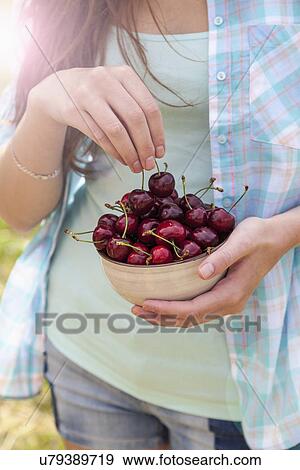 Stock Photo - Close up of young woman with bowl of cherries. Fotosearch