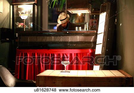 Stock Photo - Cocktail on table, bartender behind counter at bar. Fotosearch