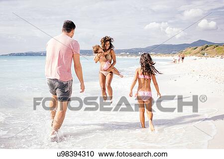 Stock Image - Couple and two girls playing on beach, Tuscany, Italy. Fotosearch