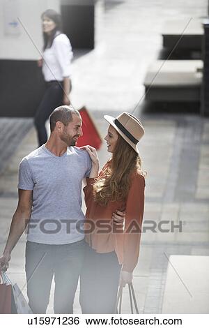 Couple in shopping mall, standing face to face, holding shopping bags View Large Photo Image Stock Photograph - Couple in shopping mall, standing face to face, holding shopping bags. Fotosearch