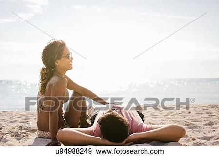 Stock Photo - Couple on beach sunbathing, Tuscany, Italy. Fotosearch