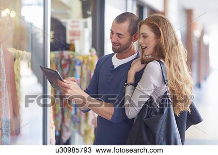 Couple window shopping, holding digital tablet View Large Photo Image Stock Image - Couple window shopping, holding digital tablet. Fotosearch