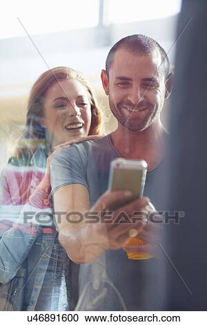 Stock Image - couple window shopping, taking photo of item in window. Fotosearch