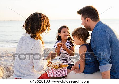 Couple with two girls having picnic on beach, Tuscany, Italy View Large Photo Image Stock Image - Couple with two girls having picnic on beach, Tuscany, Italy. Fotosearch