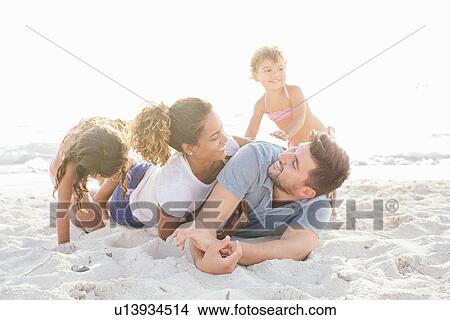 Couple with two girls play fighting on beach, Tuscany, Italy View Large Photo Image Picture - Couple with two girls play fighting on beach, Tuscany, Italy. Fotosearch