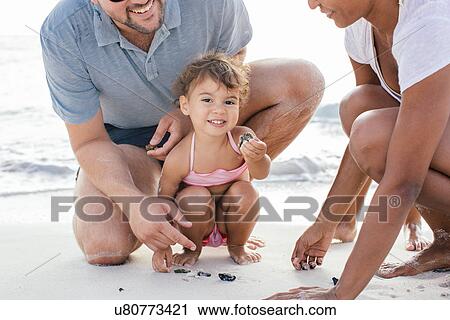 Couple with two girls searching for seashells on beach, Tuscany, Italy View Large Photo Image Stock Image - Couple with two girls searching for seashells on beach, Tuscany, Italy. Fotosearch