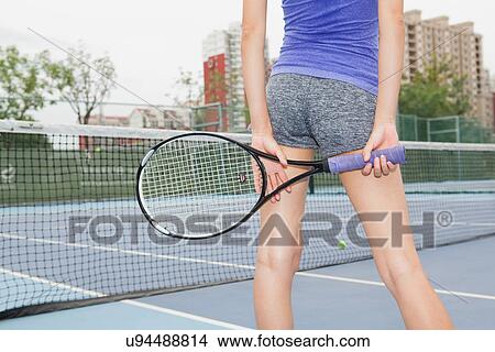 Picture - Cropped rear view of young female tennis player on tennis court. Fotosearch