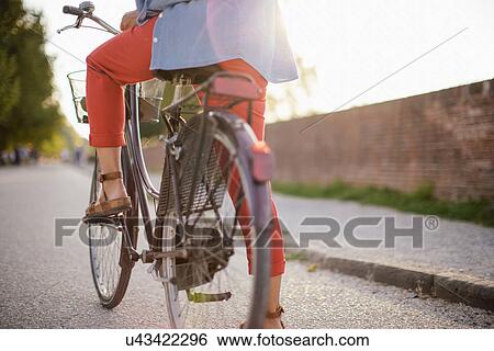 Stock Photograph - Cropped shot of mid adult woman cycling on rural road, Tuscany, Italy. Fotosearch