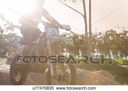 Stock Photography - Cropped shot of young male motocross racer jumping mid air down mud hill. Fotosearch