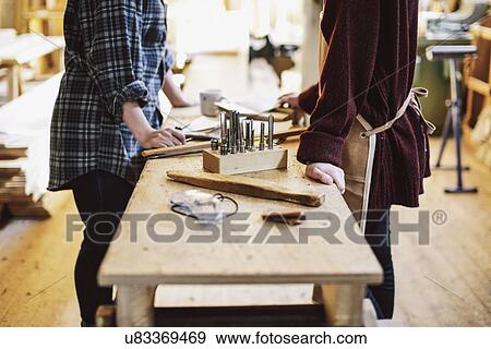 Stock Photo - Cropped view of two craftswomen at workbench in pipe organ workshop. Fotosearch