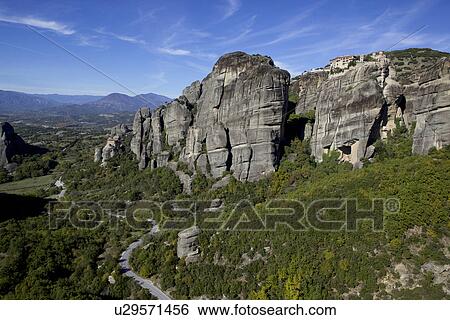 Stock Photograph - Distant view of valley and monastery built on top of rock formation, Meteora, Greece. Fotosearch