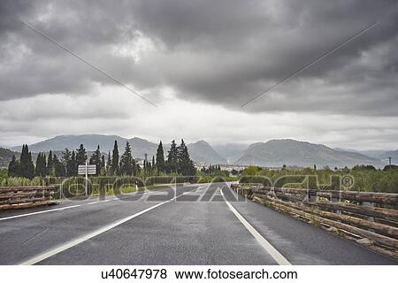 Empty road through rural scene, grey clouds above, Majorca, Spain View Large Photo Image Stock Photo - Empty road through rural scene, grey clouds above, Majorca, Spain. Fotosearch