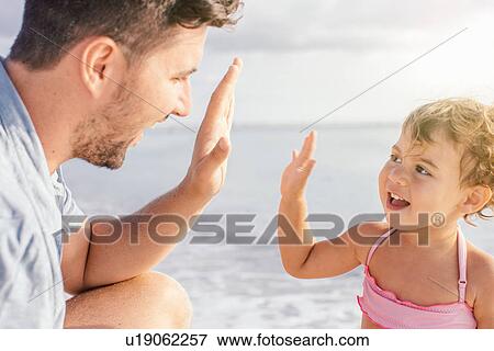 Father and toddler daughter giving high five at beach, Tuscany, Italy View Large Photo Image Stock Photo - Father and toddler daughter giving high five at beach, Tuscany, Italy. Fotosearch