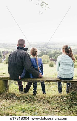 Father sitting with daughters looking at view View Large Photo Image Picture - Father sitting with daughters looking at view. Fotosearch