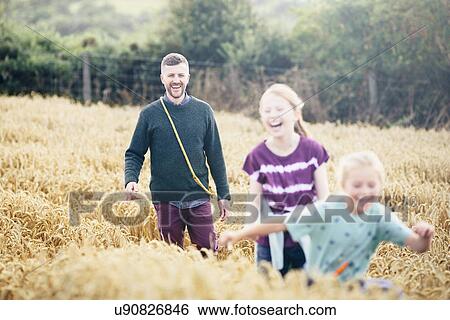 Stock Photograph - Father with two girls running through field. Fotosearch
