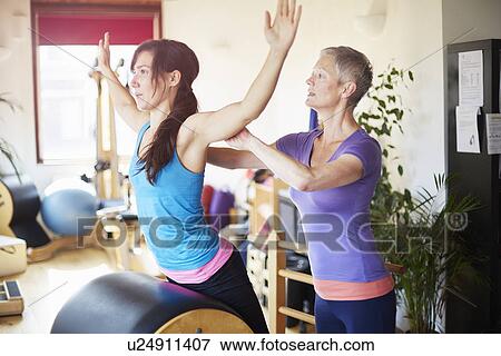 Stock Photo - Female student leaning forward onto pilates barrel in pilates gym. Fotosearch