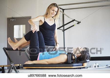 Stock Photo - Female student lying on reformer in pilates gym. Fotosearch