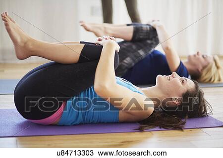 Female students lying on back hugging knees in pilates class View Large Photo Image Stock Image - Female students lying on back hugging knees in pilates class. Fotosearch