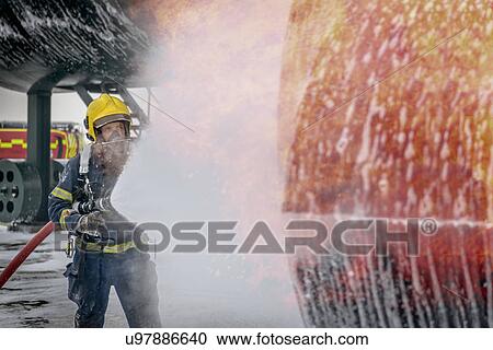 Fireman spraying water on simulated aircraft fire at training facility View Large Photo Image Stock Image - Fireman spraying water on simulated aircraft fire at training facility. Fotosearch