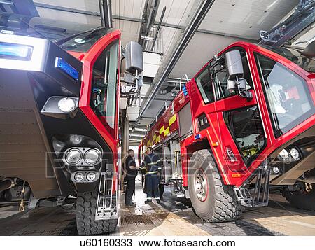 Firemen in discussion between fire engines in airport fire station View Large Photo Image Stock Image - Firemen in discussion between fire engines in airport fire station. Fotosearch