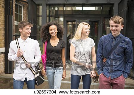 Picture - Four friends walking and smiling. Fotosearch