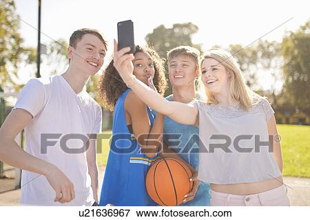 Stock Photo - Four young adult basketball players taking smartphone selfie. Fotosearch