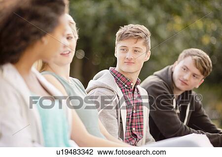 Stock Image - Four young adult friends chatting in park. Fotosearch