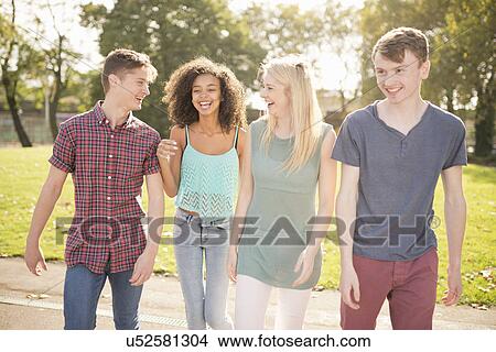 Four young adult friends strolling in park View Large Photo Image Picture - Four young adult friends strolling in park. Fotosearch