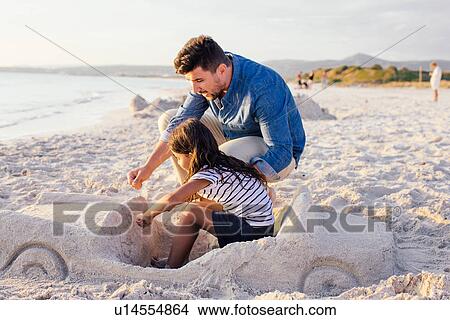 Girl and father with sophisticated car sandcastle on beach, Tuscany, Italy View Large Photo Image Picture - Girl and father with sophisticated car sandcastle on beach, Tuscany, Italy. Fotosearch