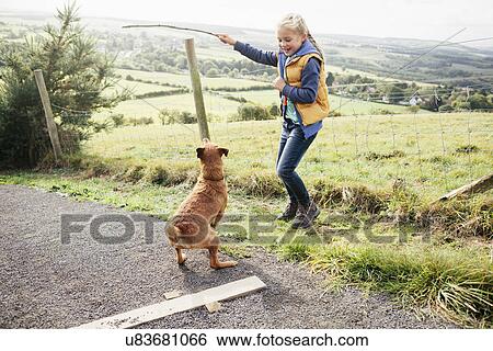 Girl holding stick for pet dog View Large Photo Image Stock Photograph - Girl holding stick for pet dog. Fotosearch