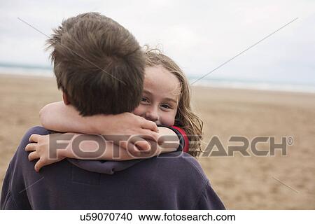 Stock Image - Girl hugging boy at beach. Fotosearch