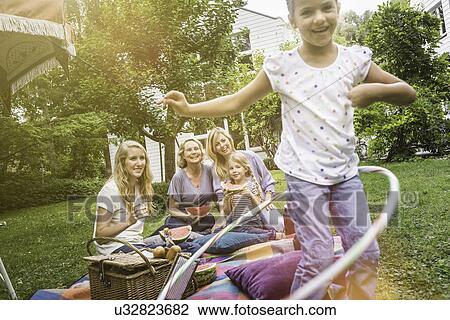 Girl playing with hula hoop at family picnic View Large Photo Image Stock Image - Girl playing with hula hoop at family picnic. Fotosearch
