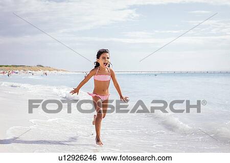 Stock Photograph - Girl running on beach, Tuscany, Italy. Fotosearch