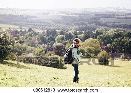 Stock Image - Girl standing in field looking at view. Fotosearch