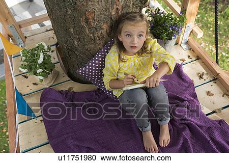 Girl with colouring book in tree house View Large Photo Image Stock Image - Girl with colouring book in tree house. Fotosearch