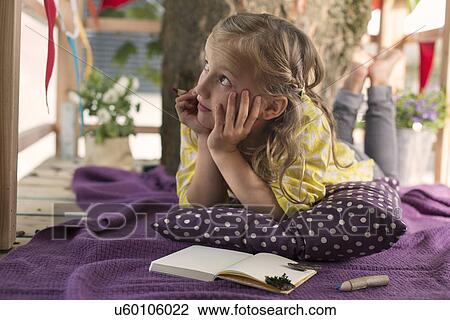 Stock Image - Girl with colouring book in tree house. Fotosearch