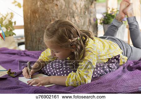 Stock Image - Girl with colouring book in tree house. Fotosearch