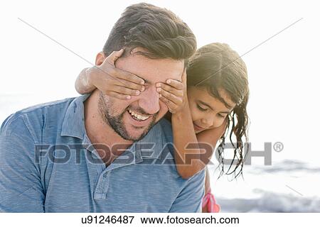 Girl with hands covering fathers eyes on beach, Tuscany, Italy View Large Photo Image Stock Photo - Girl with hands covering fathers eyes on beach, Tuscany, Italy. Fotosearch