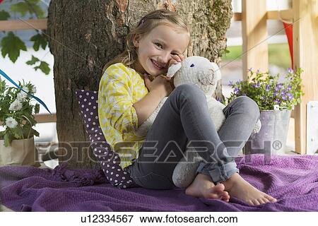 Stock Photo - Girl with soft toy in tree house. Fotosearch